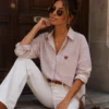 EA-Ch305-3 Maelle shirt in a pale pinkish neutral tone, seated front view with brown heart detail