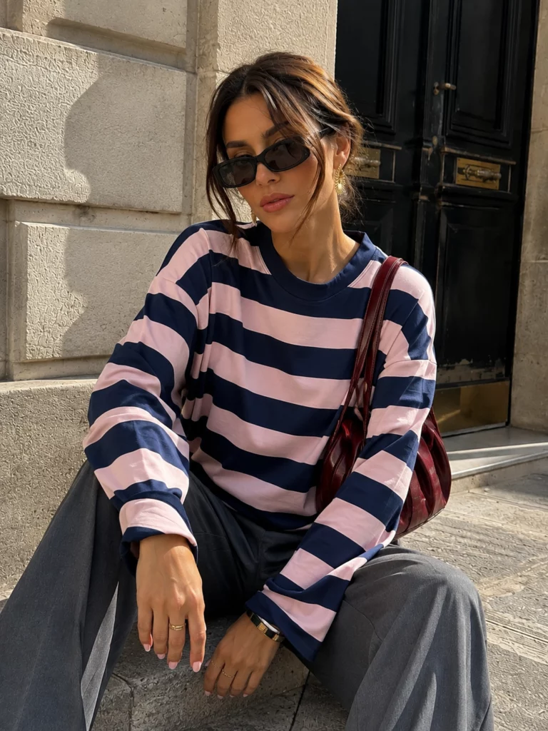 Amelie navy blue and pink striped long-sleeve T-shirt on a seated model, front detail view