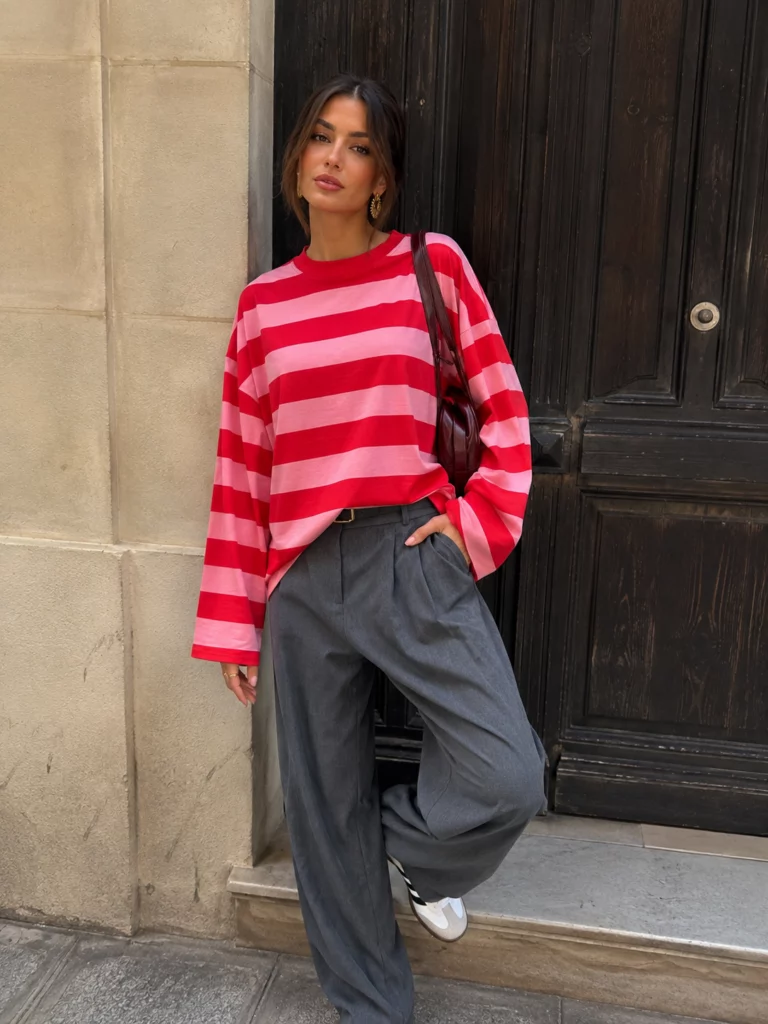 Amelie red and pink long-sleeve T-shirt on a model leaning by a doorway, front view